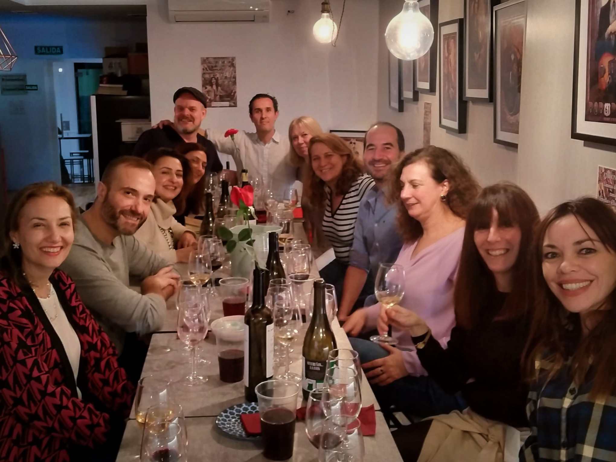 Group of people smiling at a table with drinks in a cozy setting.