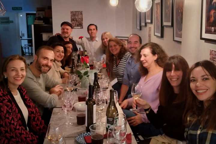 Group of people smiling at a table with drinks in a cozy setting.