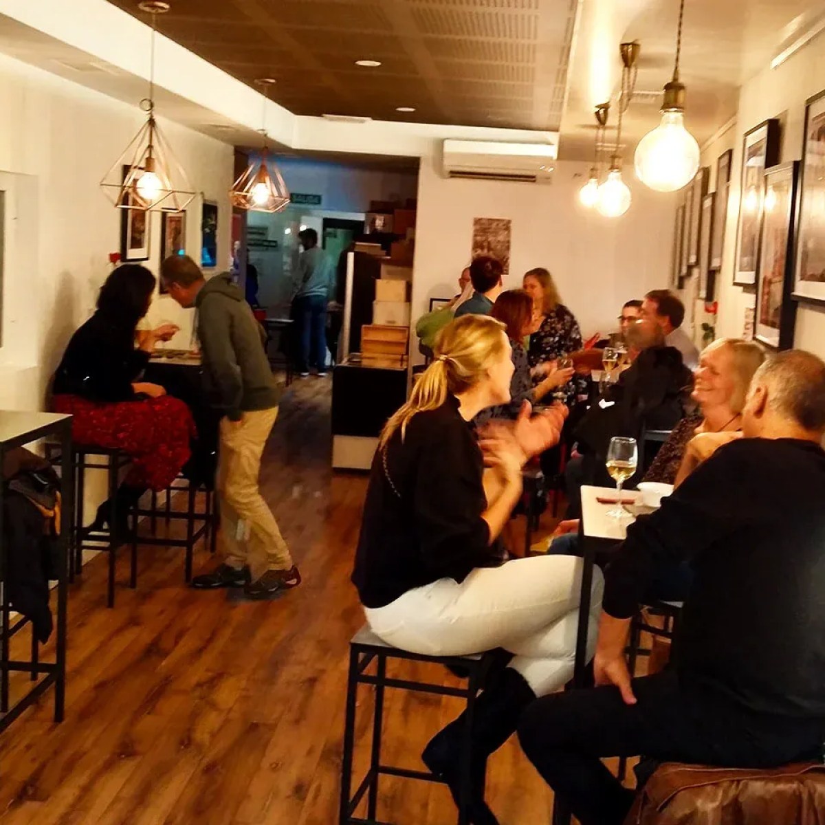 People sitting at high tables in a cozy cafe with dim lighting.