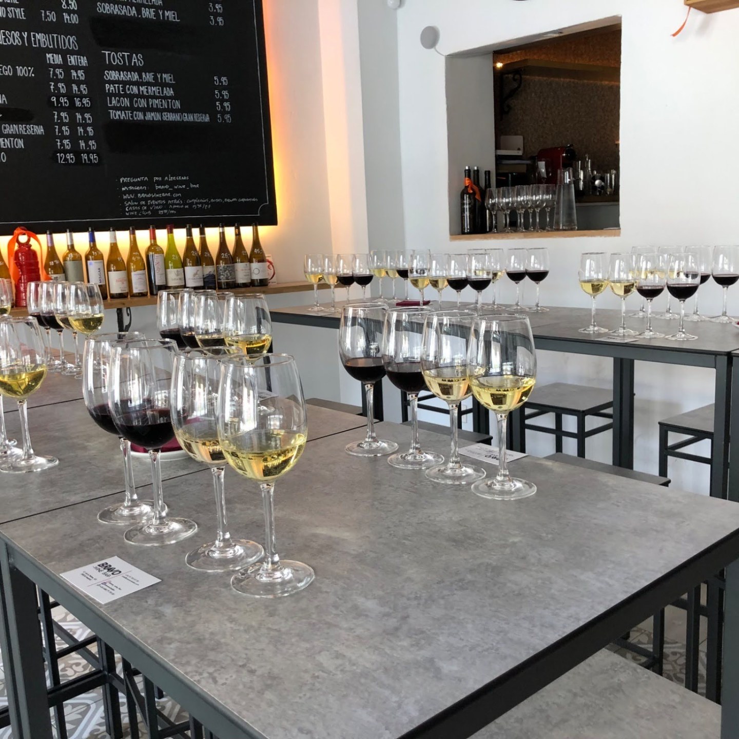 Multiple tables with wine glasses arranged for a tasting event.