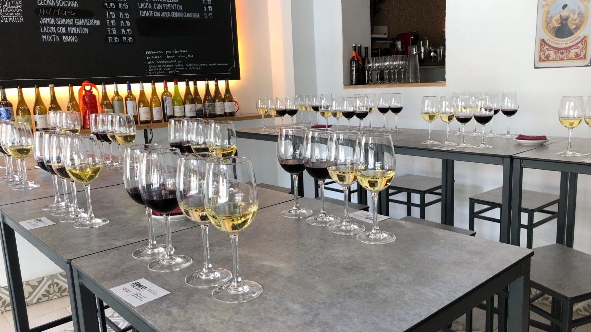 Multiple tables with wine glasses arranged for a tasting event.